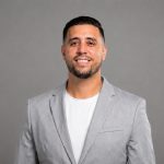Julio Sanchez, Home Advocate for Sell To Bobby, smiling in a professional gray blazer against